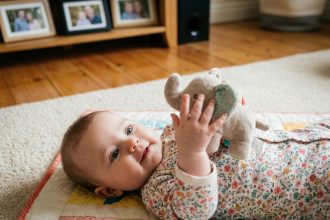 Bébé fille de 5 mois joue avec un jouet en tissu dans un salon